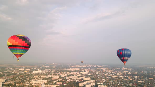 Colorful Hot Air Balloons Flying Over Buildings in Small European City at Summer Sunset, Aerial View