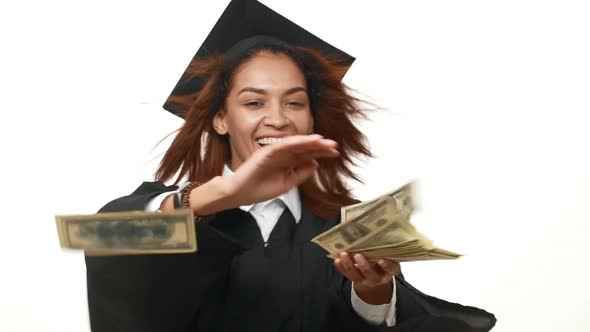 Rejoicing Happy African American Female Graduate in Black Academic Dress Throwing Dollars at Camera