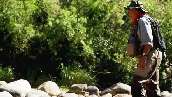 Fly fisherman standing on rock near riverside