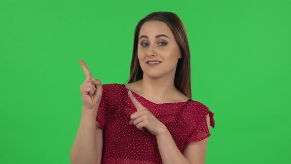 Portrait of Tender Girl in Red Dress Is Talking and Pointing Side Hand for Something, Copy Space