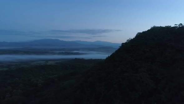 Drone footage of landscape and mountains during a sunrise.