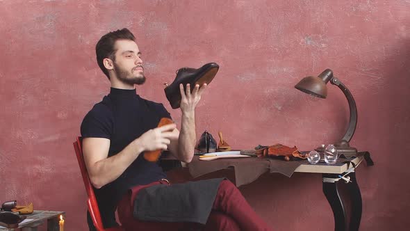 Young Man Cleaning Leather Boots While Sitting on Chair