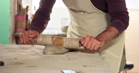 Male potter molding clay with rolling pin