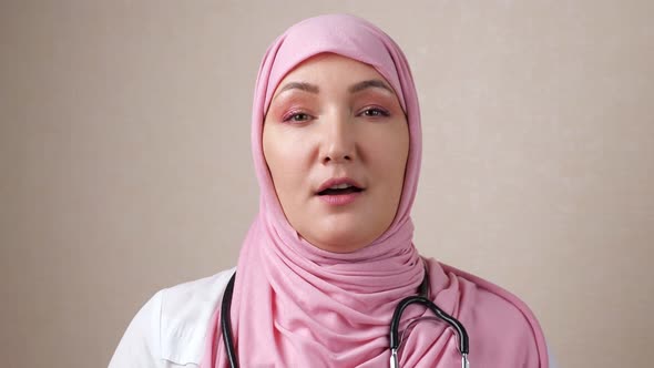 Woman Doctor in Hijab with a Phonendoscope on Neck Speaks Looking at the Camera
