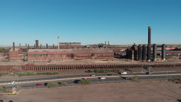 descending full aerial view of rusty old steel mill and smokestacks in industrial setting