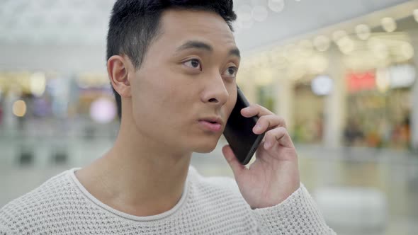 Close Up of Asian Male Talking on Phone in Shopping Center