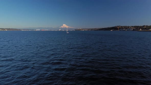 A lone sail boat in Commencement Bay of the shore of Tacoma Washington, Mount Rainier and the tide f