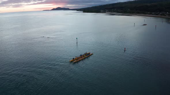 Descending aerial shot of an outrigger canoe rowing on the ocean in O'ahu, Hawaii. 4K