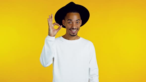 Mixed Race Hipster Man Showing Thumb Up Sign Over Yellow Background. Positive African Guy Smiles To