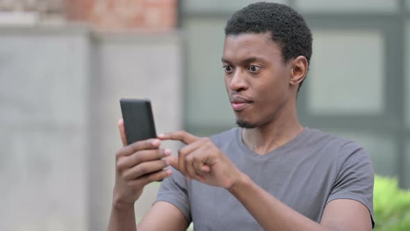 Portrait of Excited Young African Man Celebrating on Smartphone 