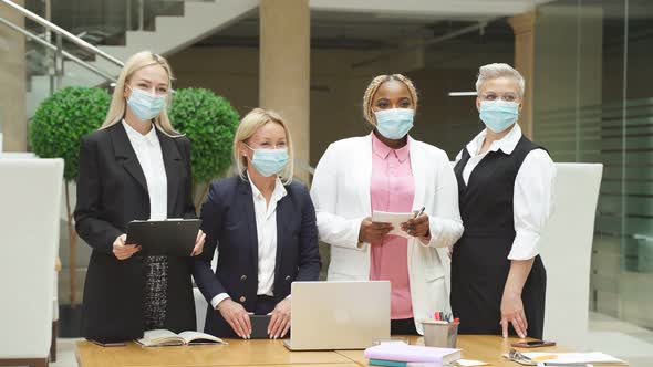 Young Team of Colleagues in Medical Masks in Office They Look at Camera