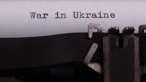 Typing phrase "War in Ukraine" on retro typewriter.