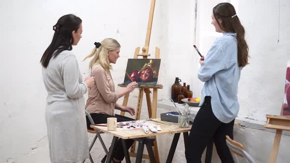 Women discussing painting during workshop in art studio