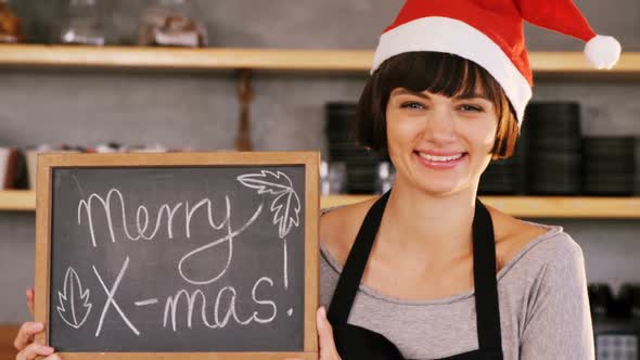 Portrait of waitress showing slate with merry x-mas sign