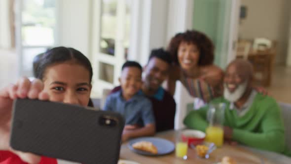 African american girl taking a selfie while having breakfast with her family at home