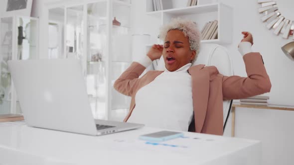 Attractive African American Woman Pulls Up and Yawns While Working with Laptop