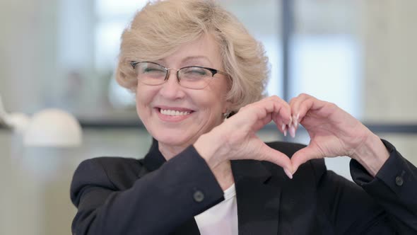 Portrait of Old Businesswoman Showing Heart Sign By Hand