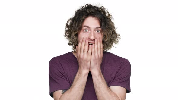 Portrait of Young Guy with Curly Hair in Casual Tshirt Covering Face in Surprise and Expressing