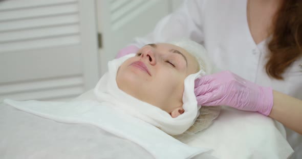 A Gloved Cosmetologist Cleans The Skin With A Napkin In A Cosmetology Clinic.