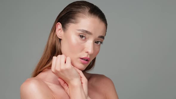 Beautiful Young Woman with Clean Fresh Skin Standing Over Light Grey Background