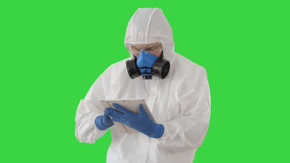 Male Doctor in Protective Suit Using Digital Tablet on a Green Screen, Chroma Key.