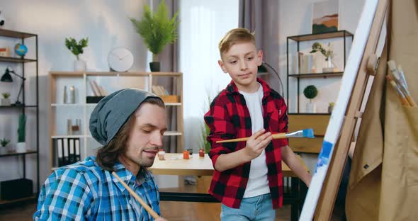 Modern Dad-Artist Drawing Picture Together with His Cute 10-Aged Son in Home Workshop