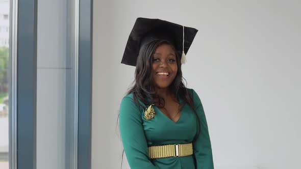 An African American Female Graduate in a Green Holiday Dress with Gold Accessories and a Square