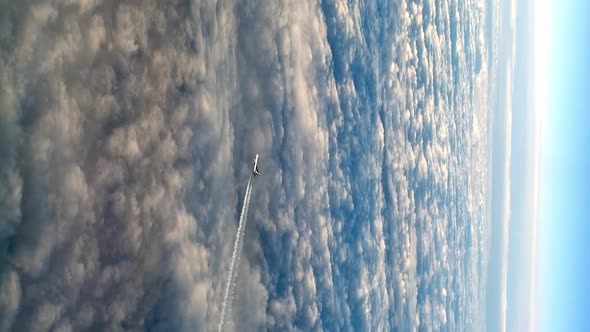 Stunning flying airplane over clouds, high angle aerial view. VERTICAL format