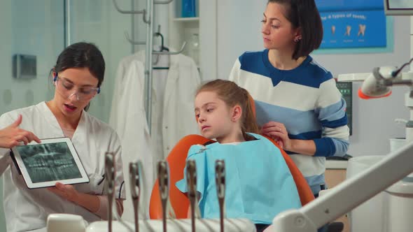 Dentistry Doctor Showing Xray of Teeth to Patient Using Tablet in Dental Clinic