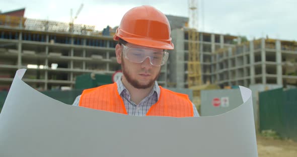 Architect Man Walking on the Construction Site and Analyzing Scheme Project Plan. Young Architect or