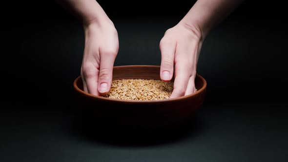 Taking Barley in Hands From Bowl on Black Background