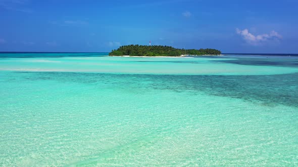 Wide above island view of a sandy white paradise beach and blue water background in colorful 4K