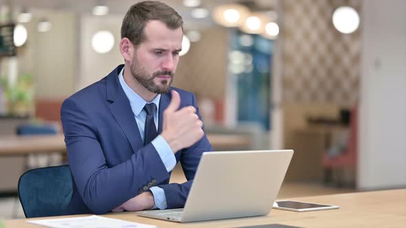 Pensive Businessman Thinking and Working on Laptop in Office