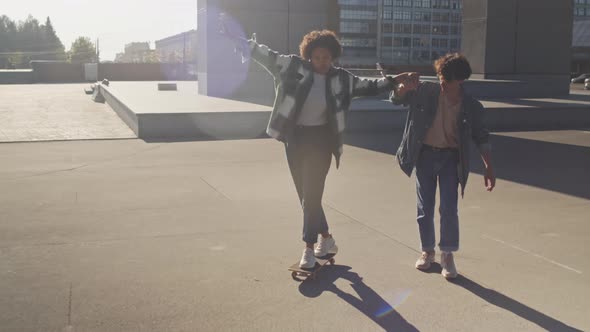 Guy Helping Girl Skateboarding