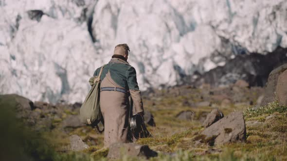 Traveller Carrying Guitar Case On Rocky Hill Next To Glacier