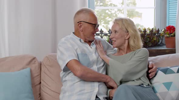 Smiling Mature Husband and Wife Hug and Relax on Sofa at Home