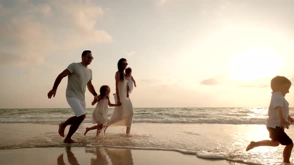 Happy Cheerful Family Running on the Beach at a Beautiful Sunset