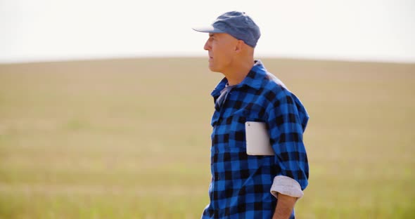 Farmer Using Digital Tablet While Looking at Tractor in Farm