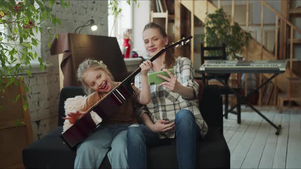 Woman and Her Daughter Playing the Guitar and Fooling Around