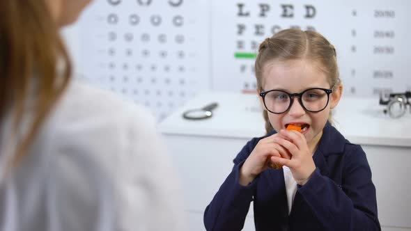 Happy Child in Glasses Eating Carrot on Recommendation of Doctor, Beta-Carotene