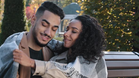 Happy Dreamy Arabian Couple Covered with Blanket Resting in Autumn Park on Bench Beautiful Woman