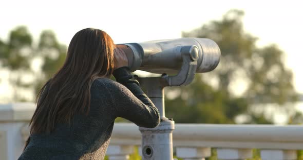 Woman tourist looking though the binocular at outdoor