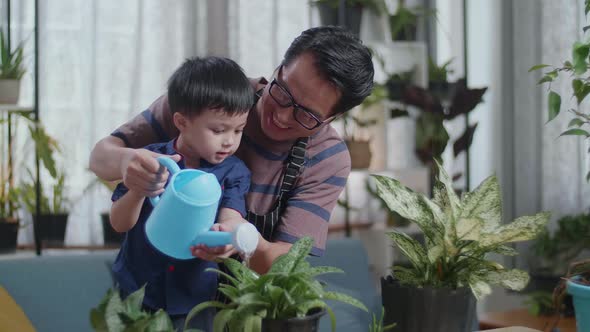 Asian Man With Son Holding Watering Pot To Water The Plants At Home