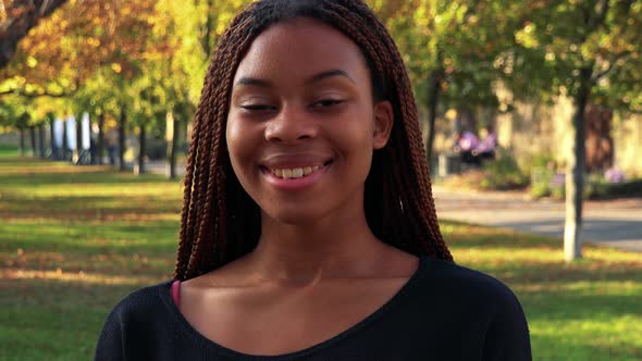 Young Beautiful Black Woman Smiles To Camera in the Park in Autumn Day