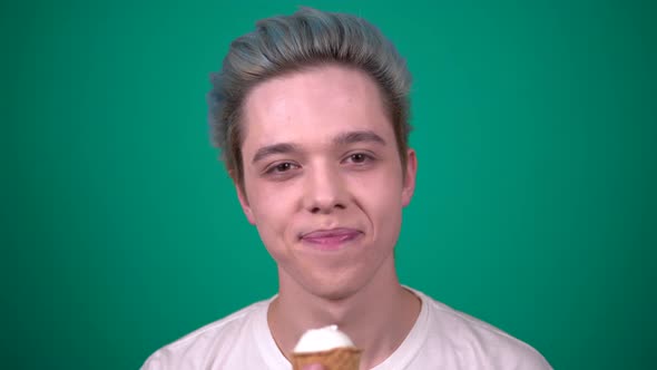 Young Happy Man with Blue Hair Eating Ice Cream in Waffle Cup Looking at Camera