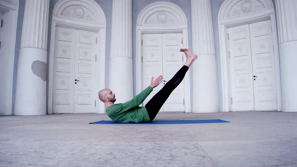 Male Yoga Instructor Performs Indoor Exercise with Lots of Doors Ardha Navasana