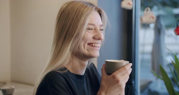 Pretty Happy Girl Smiling Sitting and Drinking Coffee in Cafelook at Camera