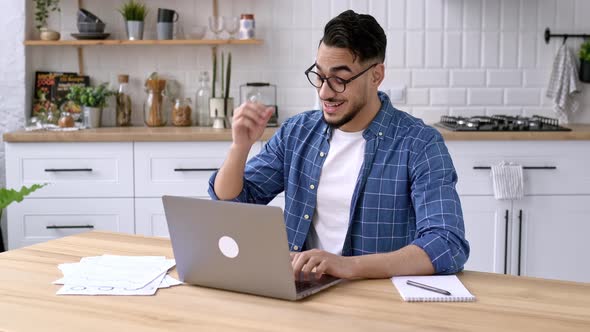 Relaxed Calm Arabian or Indian Guy Freelancer Works From Home Sits in the Kitchen at the Workplace