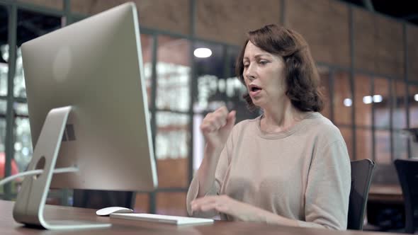 Sick Old Woman Coughing While Working on Computer