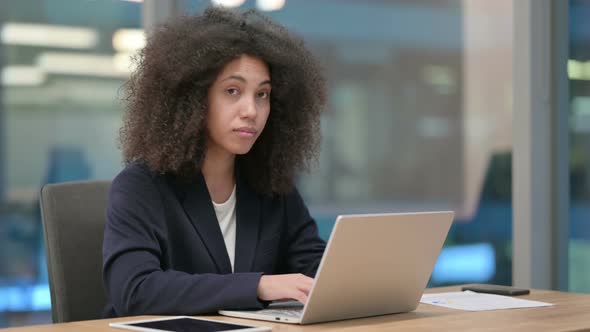 African Businesswoman with Laptop Pointing at the Camera